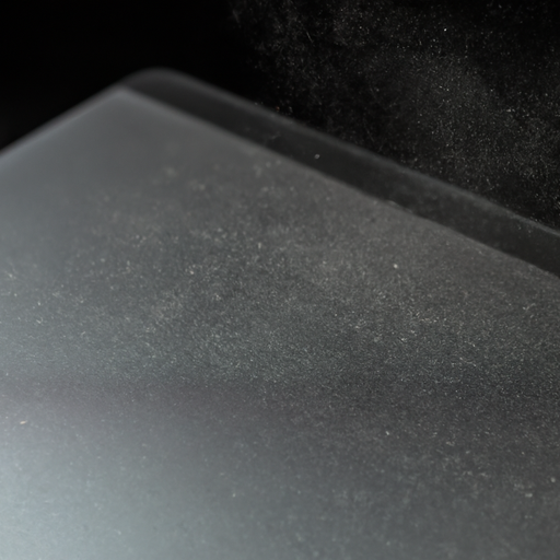 Silver macbook pro with visible dust particles against a dark background